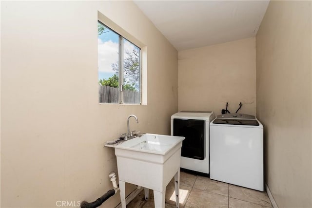laundry area with laundry area, washer and clothes dryer, a sink, and light tile patterned floors