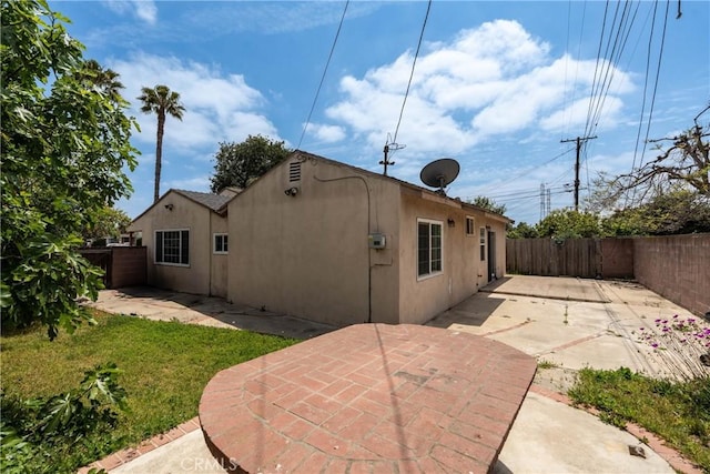 rear view of house featuring a fenced backyard, a patio area, and stucco siding