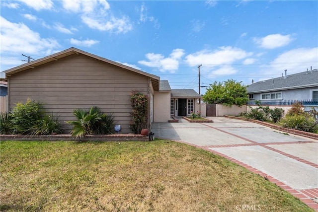 single story home featuring fence, a patio, driveway, and a front lawn