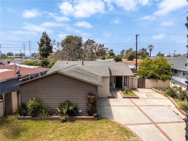 ranch-style home with fence, a shingled roof, driveway, and a front lawn