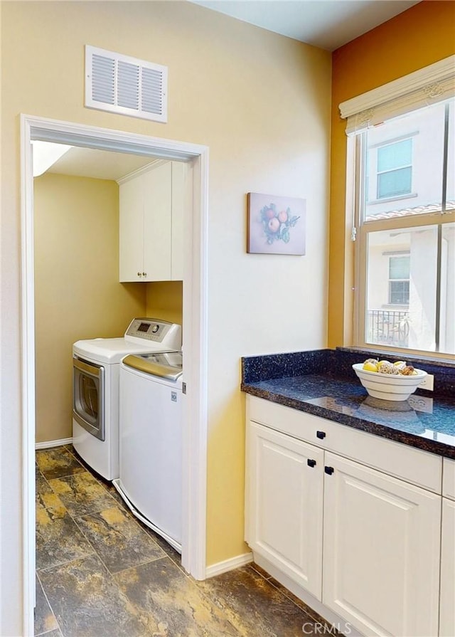 laundry area with cabinet space, separate washer and dryer, baseboards, stone finish flooring, and visible vents