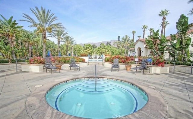 view of swimming pool featuring a mountain view, a hot tub, and a patio area