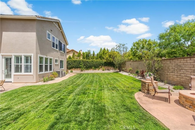 view of yard with central AC, a fire pit, and a patio area