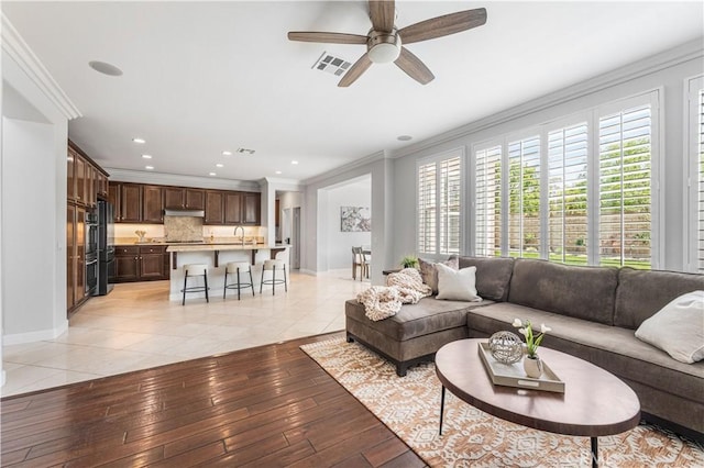 living area with ornamental molding, a ceiling fan, light tile patterned floors, baseboards, and recessed lighting