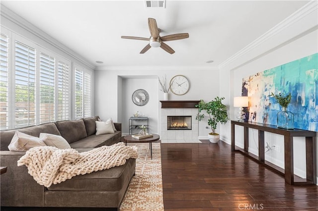 living room featuring a ceiling fan, hardwood / wood-style flooring, crown molding, a fireplace, and baseboards