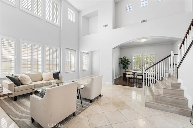 living room with arched walkways, a high ceiling, stairway, light tile patterned floors, and baseboards