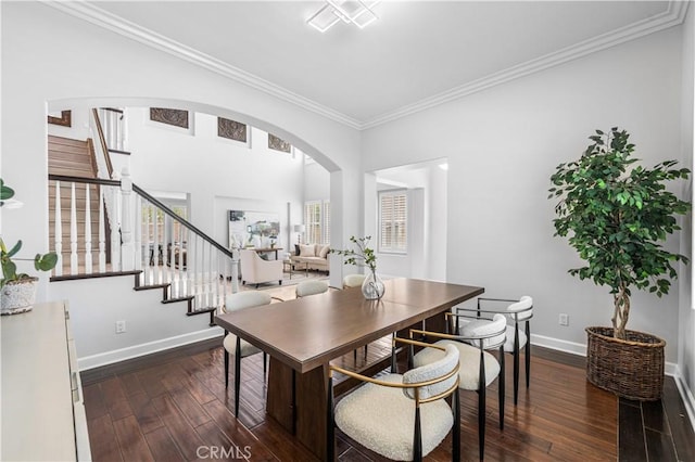 dining space featuring dark wood-type flooring, stairway, crown molding, baseboards, and arched walkways