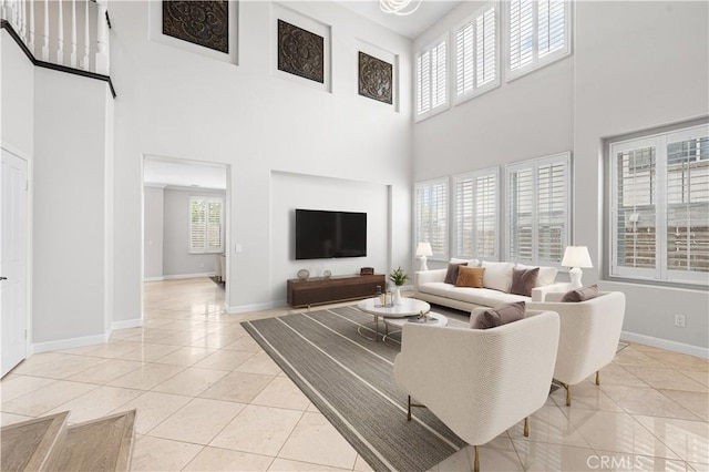 living room featuring a towering ceiling, light tile patterned floors, and baseboards