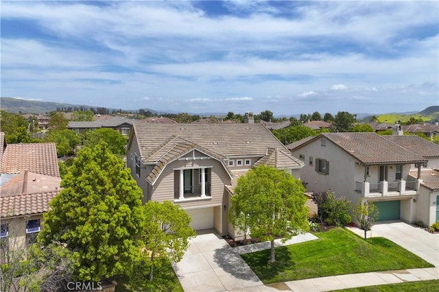 view of front of house featuring a garage, driveway, a residential view, and a tile roof