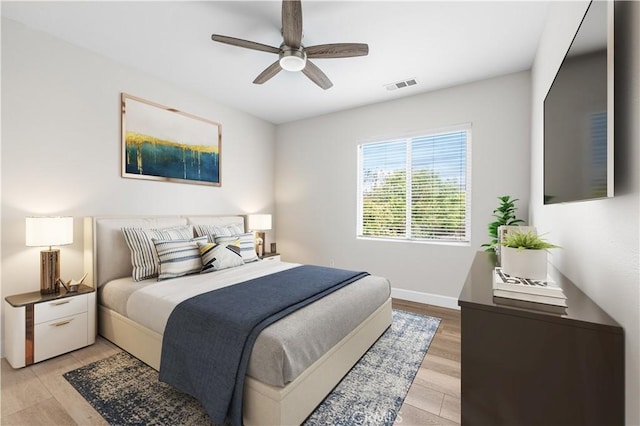 bedroom with light wood-style floors, ceiling fan, and baseboards