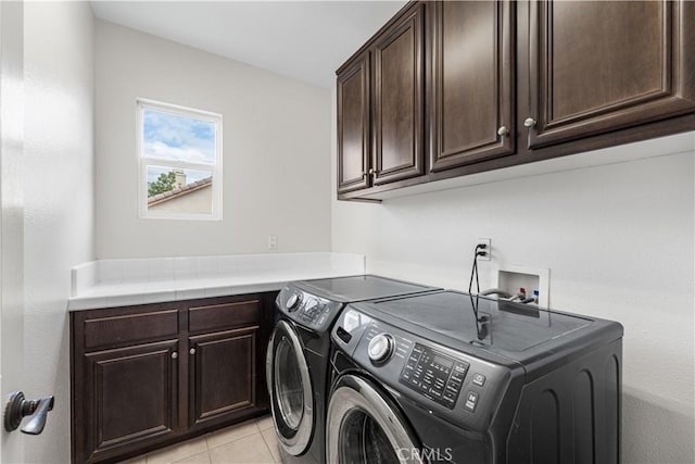 washroom with cabinet space, independent washer and dryer, and light tile patterned floors