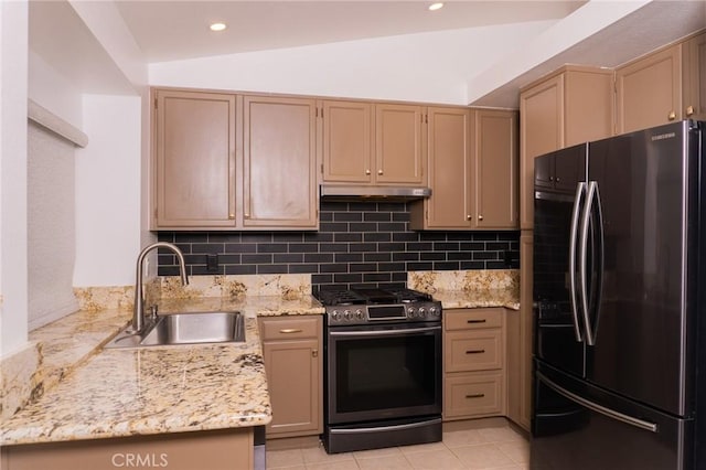 kitchen with freestanding refrigerator, stainless steel gas range, under cabinet range hood, a sink, and backsplash