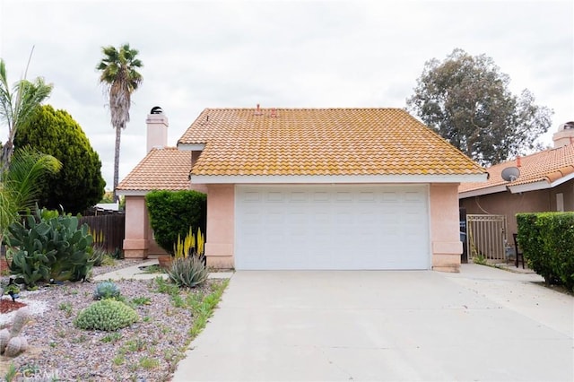 view of front facade with a garage, fence, stucco siding, and a tile roof