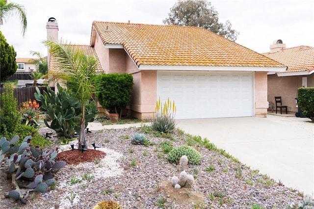 view of front of property featuring fence, a garage, stucco siding, a tiled roof, and driveway