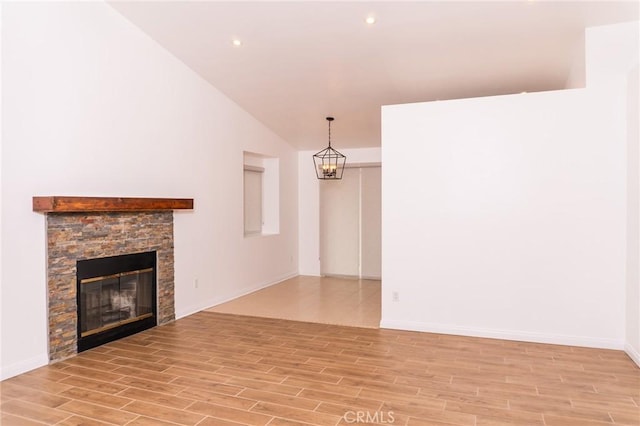 unfurnished living room featuring a fireplace, a notable chandelier, baseboards, lofted ceiling, and light wood-style flooring
