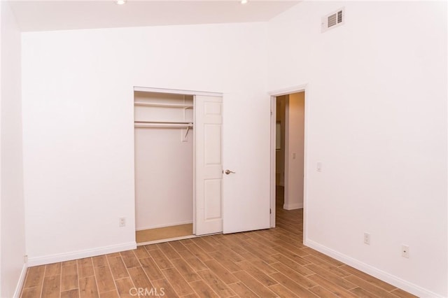 unfurnished bedroom with visible vents, wood finished floors, baseboards, a closet, and recessed lighting