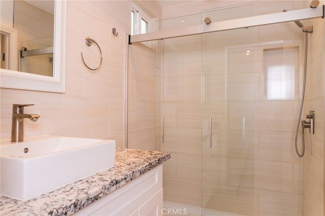 full bath featuring tile walls, a shower stall, and vanity