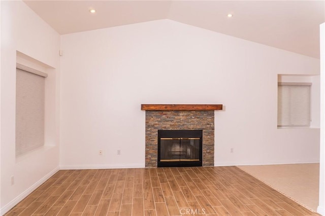unfurnished living room with wood finished floors, recessed lighting, lofted ceiling, and a fireplace