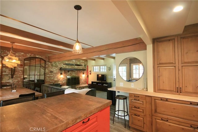 kitchen featuring beam ceiling, a fireplace, open floor plan, light wood-type flooring, and arched walkways