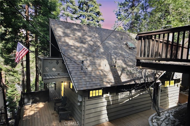exterior space with a deck and a shingled roof