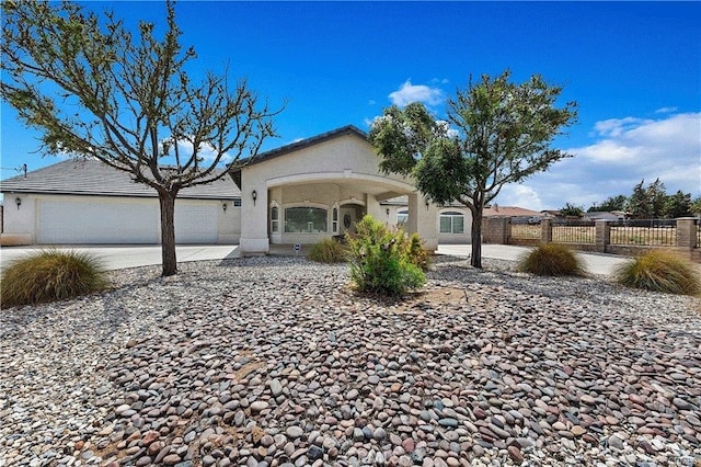 view of front of home with stucco siding, a garage, fence, and driveway