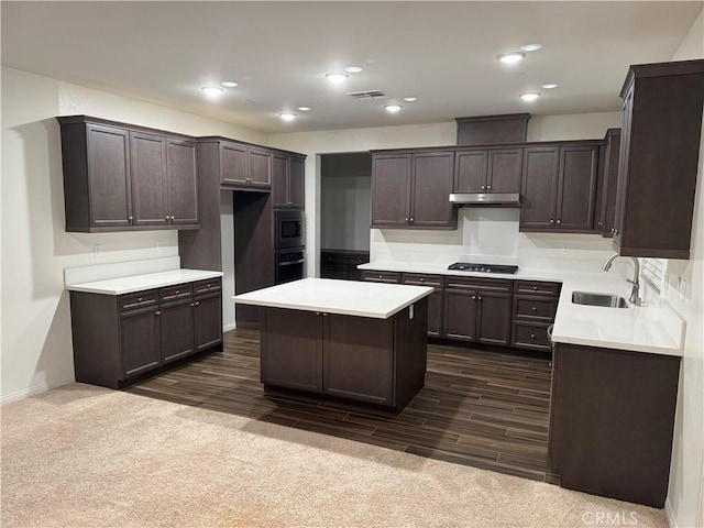 kitchen featuring dark brown cabinetry, oven, stainless steel microwave, under cabinet range hood, and a sink