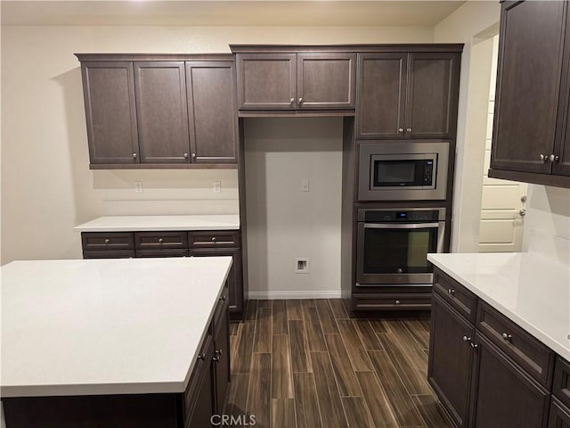 kitchen featuring dark brown cabinets, wood finish floors, and appliances with stainless steel finishes