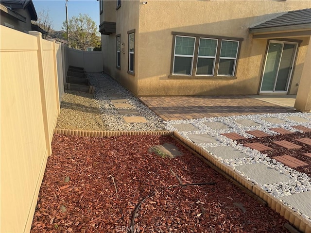 view of side of property with a fenced backyard and stucco siding