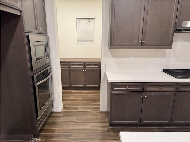 kitchen with light countertops, stainless steel appliances, dark wood finished floors, and dark brown cabinets