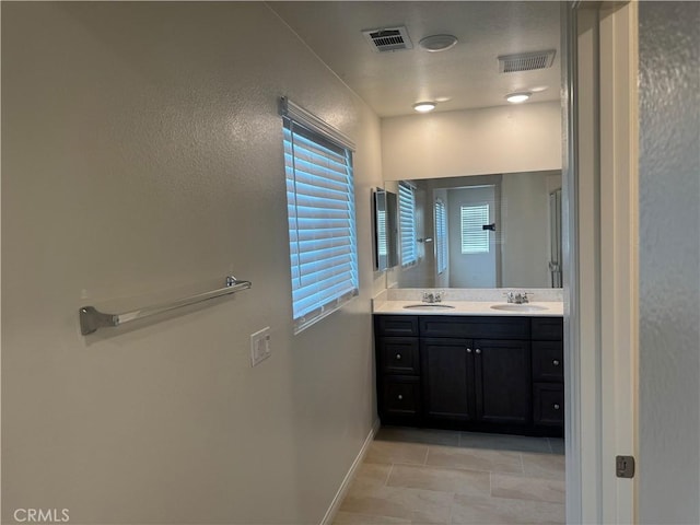 full bath featuring visible vents, a sink, baseboards, and double vanity
