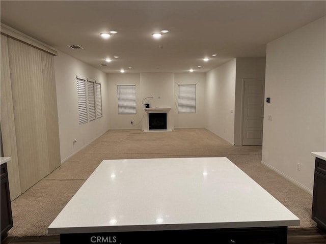 unfurnished living room featuring visible vents, recessed lighting, a fireplace, and light carpet