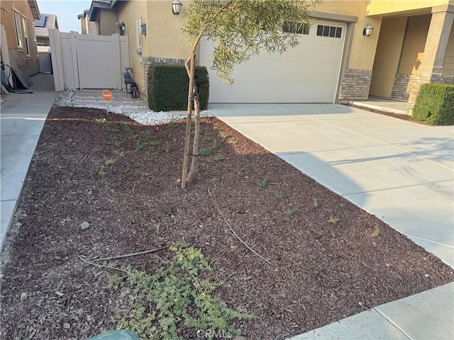 view of yard featuring a garage, fence, and concrete driveway