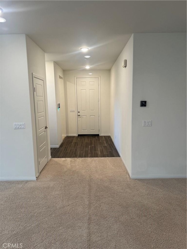hall featuring baseboards and dark carpet