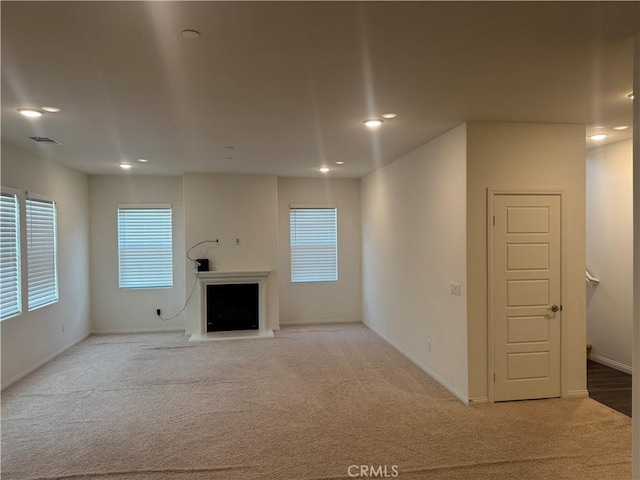 unfurnished living room with visible vents, a fireplace, baseboards, carpet, and recessed lighting