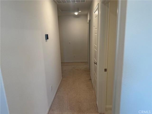 corridor featuring baseboards, visible vents, and light carpet