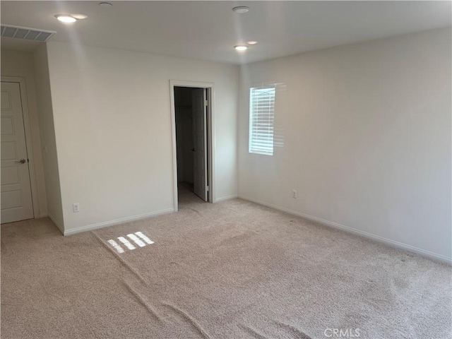 unfurnished bedroom featuring baseboards, visible vents, light carpet, and a walk in closet