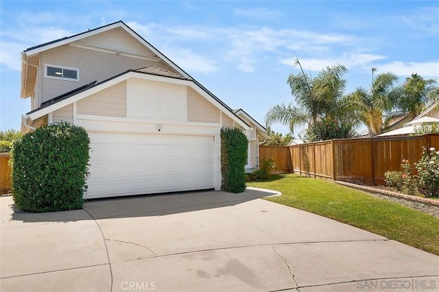exterior space featuring an attached garage, a lawn, fence, and driveway