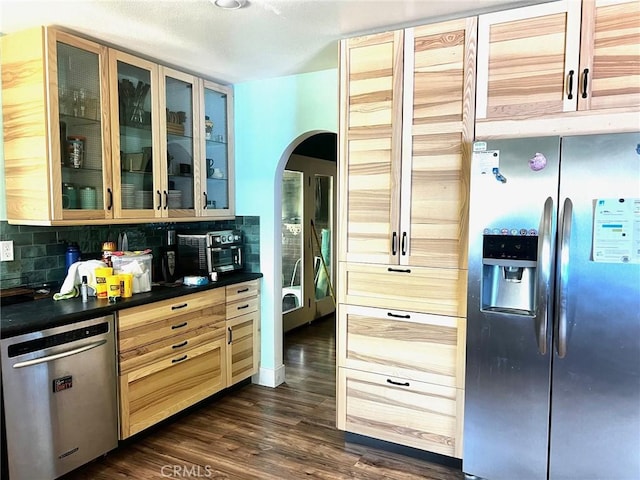 3324 Columbia Ave, Merced, CA 95340 - kitchen featuring decorative backsplash, dark countertops, glass insert cabinets, arched walkways, and stainless steel appliances
