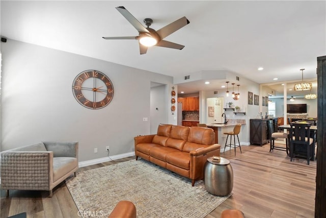 living area featuring light wood-style floors, a ceiling fan, baseboards, and visible vents
