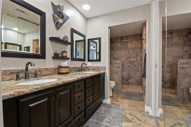 bathroom with a sink, a shower stall, toilet, and visible vents
