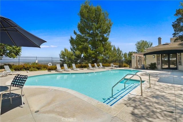 community pool with a patio, fence, and french doors
