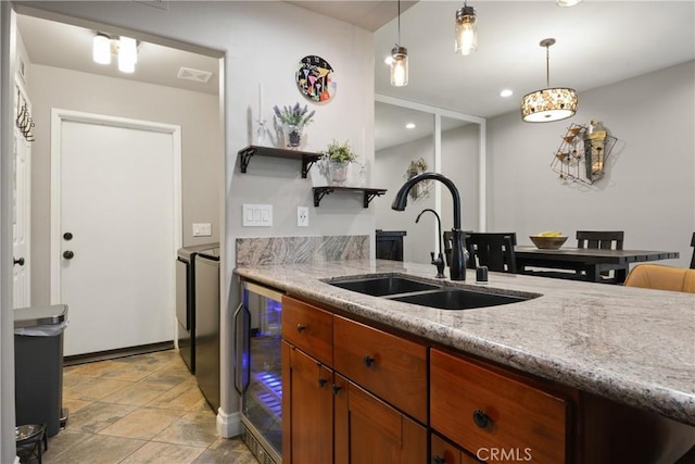 kitchen featuring open shelves, wine cooler, light stone countertops, a sink, and decorative light fixtures