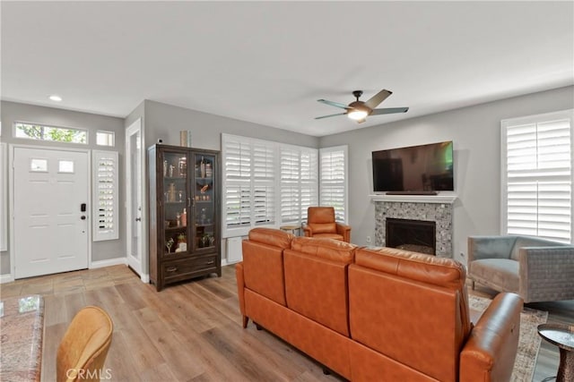 living area featuring ceiling fan, a fireplace, light wood-style floors, recessed lighting, and baseboards