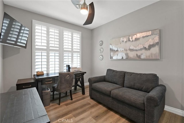 office space featuring baseboards, ceiling fan, and wood finished floors