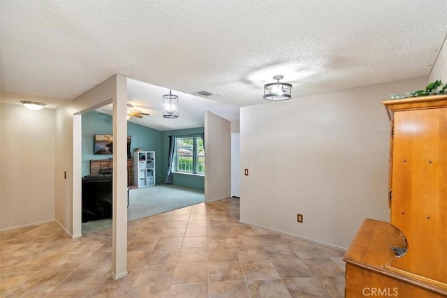 interior space featuring baseboards, a fireplace, a textured ceiling, and visible vents