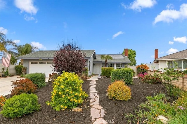 view of front of property with fence, roof mounted solar panels, concrete driveway, an attached garage, and stucco siding