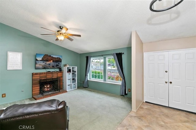 living room with ceiling fan, a fireplace, a textured ceiling, and lofted ceiling