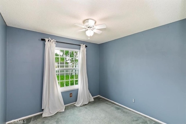 empty room with carpet floors, a ceiling fan, a textured ceiling, and baseboards