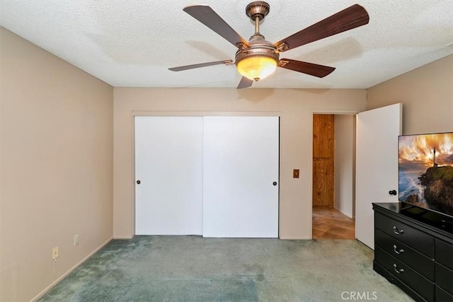 unfurnished bedroom with a textured ceiling, light carpet, ceiling fan, and a closet