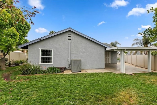 rear view of property with central AC unit, fence, a yard, a patio, and stucco siding
